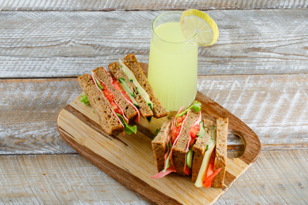 vegetable sandwich with cheese ham lemonade wooden cutting board high angle view scaled